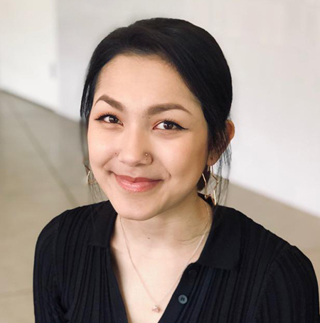 Smiling person with hair pulled back and a dark v-neck blouse