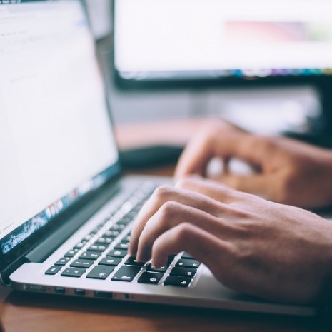 Two hands typing on a laptop