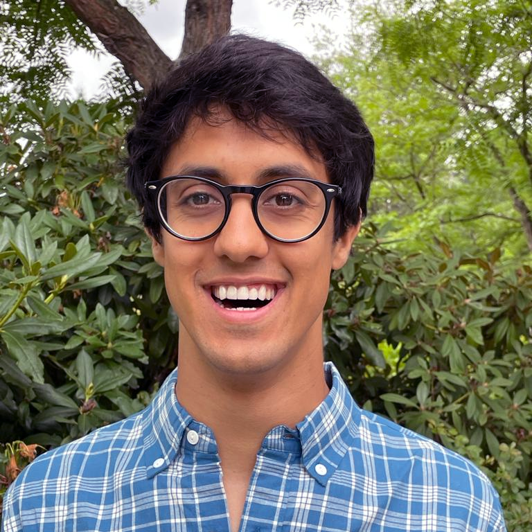 Smiling person in a plaid shirt with glasses